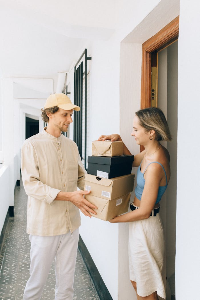 Woman Receiving a Package from a Delivery Man in front of Apartment